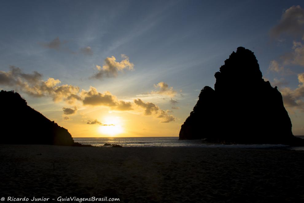 Imagem do sol se pondo atrás do Morro Dois Irmãos.